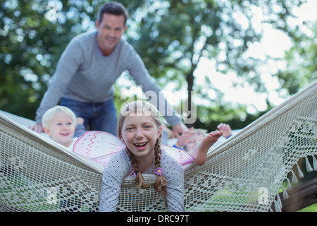 Padre e figli che stabilisce in amaca all'aperto Foto Stock