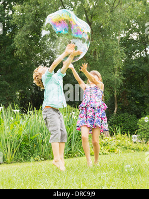 Bambini che giocano con bolla di all'aperto Foto Stock