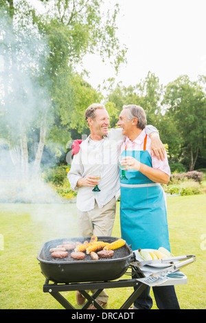 Gli uomini abbraccia al barbecue nel cortile posteriore Foto Stock