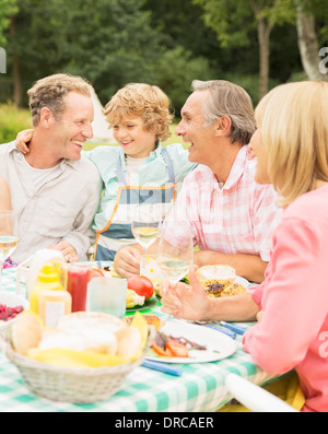 Famiglia godendo il pranzo a tavola in cortile Foto Stock