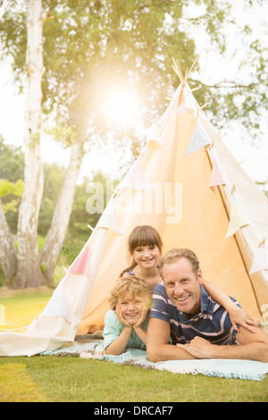 Padre e figli rilassante in teepee nel cortile posteriore Foto Stock