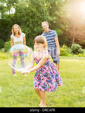 La famiglia gioca con bolle nel cortile posteriore Foto Stock