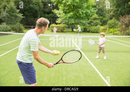 Famiglia giocando a tennis su erba corte Foto Stock