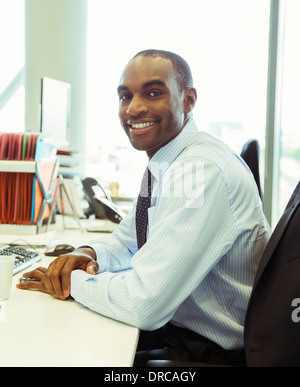 Imprenditore sorridente alla scrivania in ufficio Foto Stock