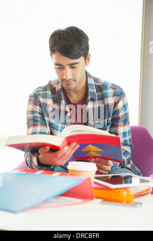 Studente universitario la lettura di un libro di testo nella lounge Foto Stock