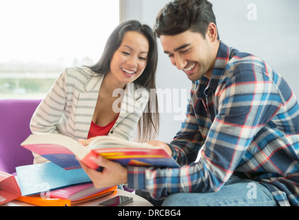 Gli studenti universitari la lettura di un libro di testo nella lounge Foto Stock