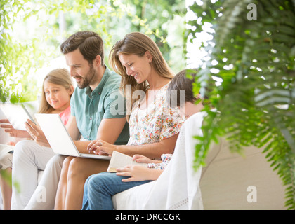 Lettura di famiglia e utilizzando la tecnologia sul patio Foto Stock