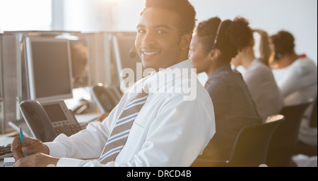 Imprenditore con auricolare sorridente in ufficio Foto Stock