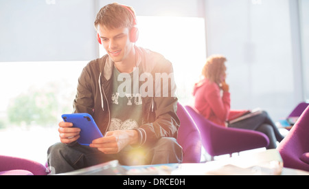 Studente universitario ascoltando le cuffie nella lounge Foto Stock