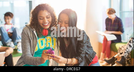 Gli studenti universitari tramite telefono cellulare nella lounge Foto Stock