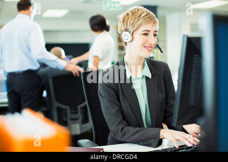 Imprenditrice parlando su auricolare in carica Foto Stock