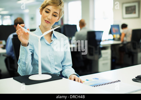 Imprenditrice esaminando toy turbina eolica in ufficio Foto Stock