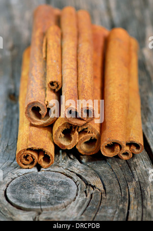 Bastoncini di cannella nella benna su sfondo di legno Foto Stock