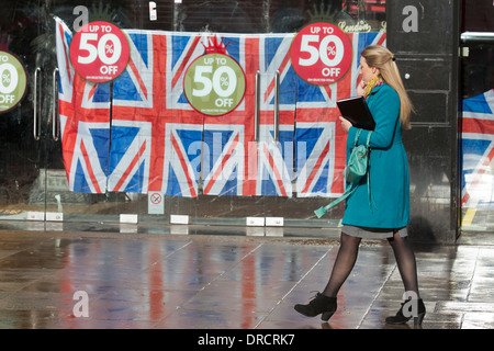 Una donna cammina oltre l'ex HMV store ora decorate con unione di bandiere e di prezzo off-segni, Coventry Street, Londra, Regno Unito Foto Stock