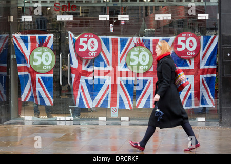 Una donna cammina oltre l'ex HMV store ora decorate con unione di bandiere e di prezzo off-segni, Coventry Street, Londra, Regno Unito Foto Stock