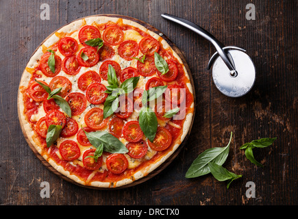 La pizza italiana con pomodorini e il verde del basilico sul tavolo di legno Foto Stock