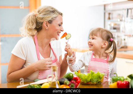 Kid figlia madre di alimentazione verdure in cucina Foto Stock