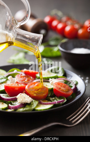 Versando l'olio d'oliva su insalata con pomodori e cetrioli Foto Stock