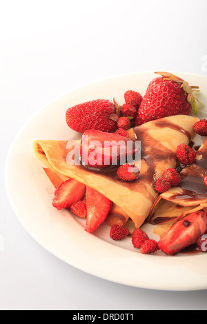 Frittelle con differenti le fragole con lo sciroppo di cioccolato su bianco Foto Stock