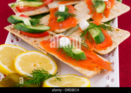 Sandwich di salmone con lattuga fresca e cetriolo sottaceto, cipolla, succo di limone sulla piastra. Foto Stock