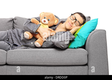 Giovane ragazzo che dorme sul divano tenendo un orsacchiotto Foto Stock