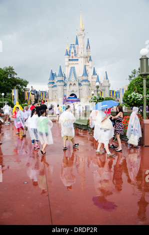 Famiglie di ponchos in caso di pioggia presso il Walt Disney World, a Orlando, Florida con il Regno di Magic Castle in background. Foto Stock