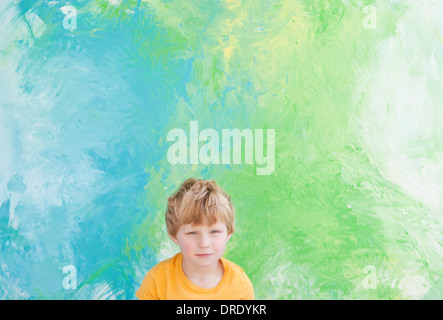 Ragazzo seduto davanti di verde e di blu dipinto Foto Stock