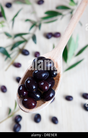 Le olive in un cucchiaio di legno Foto Stock