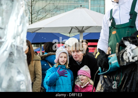 I bambini guardano su come un artista che lavora per creare una scultura come parte del London Ice Sculpture Festival 2014 Foto Stock