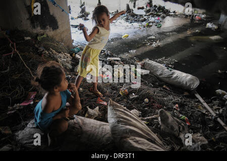 Paranaque, Filippine. 24 gen 2014. Bambini filippini giocare sotto un ponte affollato che utilizzano come un rifugio in Paranaque, suburbana Manila, Filippine, 24 gennaio 2014. Tra le acque al di sotto e il traffico che attraversa il sovraccarico, molte le famiglie filippine pilotato dalla povertà hanno istituito le residenze di fortuna sotto i ponti. Secondo le Nazioni Unite, un decimo di baraccati vivono in Metro Manila con 80.000 persone per chilometro quadrato in alcuni quartieri.Foto: Ezra Acayan/NurPhoto © Ezra Acayan/NurPhoto/ZUMAPRESS.com/Alamy Live News Foto Stock