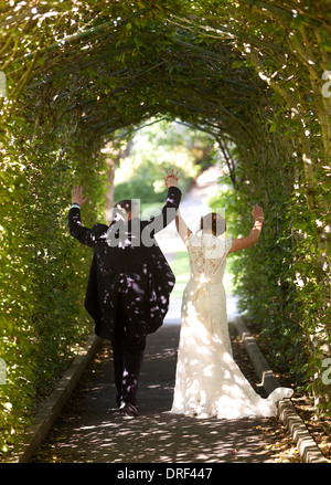 Appena una coppia sposata a celebrare in modo arco Foto Stock