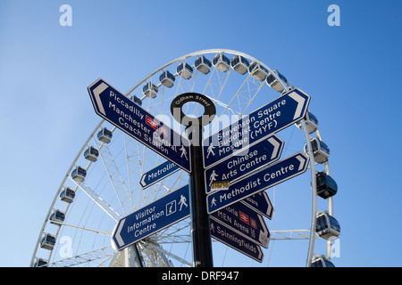 Un cartello stradale con destinazioni diverse. Le posizioni e le direzioni, Oldham Street Multi-Directional  Piccadilly cartello turistico e il grande Ferris siamo Foto Stock