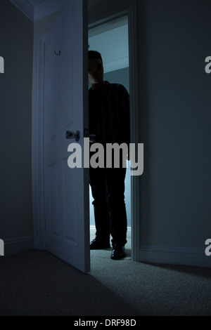 Silhouette di un uomo in piedi al buio in un aperto porta. Foto Stock