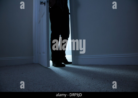 Silhouette di un uomo in piedi al buio in un aperto porta. Foto Stock