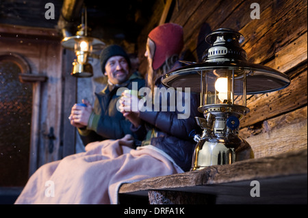 Giovane seduto sulla panca in legno nella parte anteriore del Log Cabin, Tirolo, Austria, Europa Foto Stock