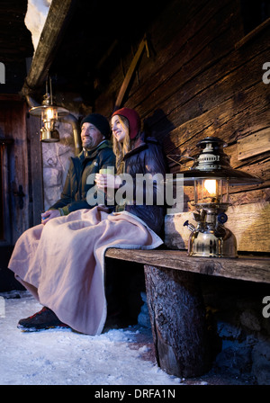 Giovane seduto su un banco di lavoro nella parte anteriore del Log Cabin, Tirolo, Austria, Europa Foto Stock