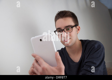 Buona ricerca giovane con gli occhiali, tenendo in mano un bianco digitale compressa. La forma del paesaggio, con copia spazio. Foto Stock