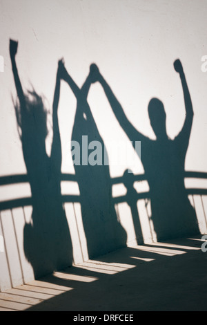 Foto Creative di persone contente e ombre sul muro bianco tenendo le mani Foto Stock