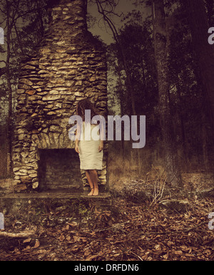 La donna appoggia contro il camino di pietra nel bosco Foto Stock