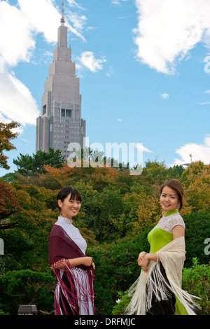 Due giovani donne nei tradizionali Ao Dai in Shinjuku Park nella parte anteriore del NTT Docomo edificio Yoyogi Foto Stock