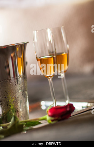 Champagne flauti accanto a secchiello per il ghiaccio e un single rose Foto Stock