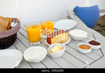 Greco tradizionale prima colazione con yogurt, succo d'arancia, torta, marmellata, miele e pane. Foto Stock