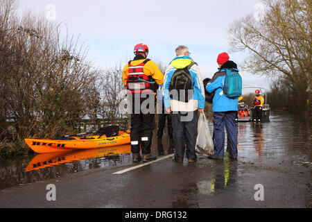 Muchelney, Somerset, Regno Unito. Il 25 gennaio 2014. Gli abitanti di un villaggio di Muchelney attesa di imbarcarsi sul traghetto azionato da Devon e Somerset fuoco e il servizio di soccorso tra il villaggio isolato di Muchelney e Langport attraverso l'allagato Somerset livelli. Foto Stock