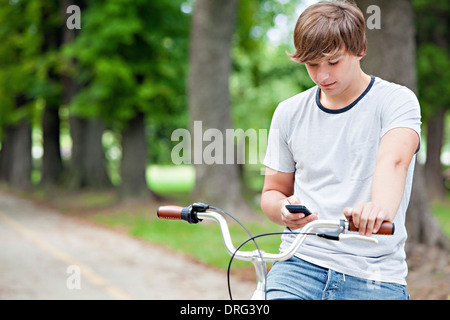 Giovane con bicicletta utilizzando il telefono cellulare, osijek, Croazia Foto Stock