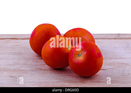Pomodori interi su invecchiato boarrd trinciatura su sfondo bianco. closeup Foto Stock