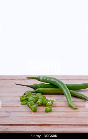 Un trito di peperoncini verdi con la pila di peperoncini verdi su invecchiato boarrd chopping e sfondo bianco.vertical Foto Stock