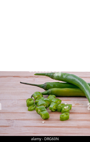 Un trito di peperoncini verdi con la pila di peperoncini verdi su invecchiato boarrd chopping e sfondo bianco verticale. Foto Stock