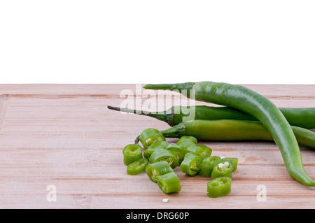 Un trito di peperoncini verdi con la pila di peperoncini verdi su invecchiato boarrd chopping e sfondo bianco. orizzontale Foto Stock