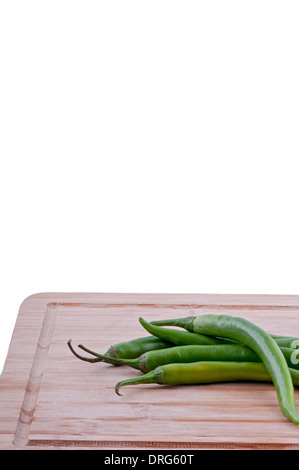 Pila di peperoncini verdi su invecchiato boarrd chopping e sfondo bianco. vista laterale Foto Stock