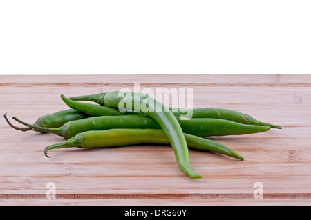 Pila di peperoncini verdi su invecchiato boarrd chopping e sfondo bianco. orizzontale Foto Stock